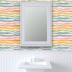 a bathroom sink sitting under a mirror next to a wall mounted faucet in front of a striped wall