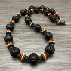 This bold long necklace is made of 20mm black large chunky fluted wooden beads with red, gold, green ceramic rondelle beads and 8mm black lava stone beads. It has a stainless steel lobster claw style clasp with stainless steel wire guards. Available in lengths of 28 and 30 inches. Prices vary. Wooden Beads Necklace, Beaded Necklace Men, Necklace Painting, Rasta Flag, Beaded Necklace For Men, Jamaican Colors, Wood Beads Jewelry, Large Bead Necklace, Bead Accessories