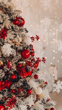 a white christmas tree with red ornaments and snowflakes on it's branches