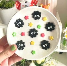 a hand holding a white plate with black and yellow decorations on it