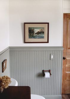 a bathroom with a sink, toilet and painting on the wall above it's door