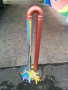 an orange and blue umbrella stand on the sidewalk with paint splattered all over it