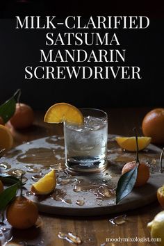 a glass filled with water sitting on top of a table next to sliced oranges