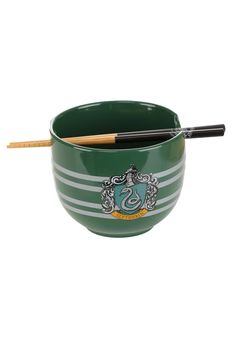 a green bowl with two chopsticks in it and a crest on the side