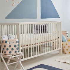 a baby's room with a crib, chair, rug and wall art