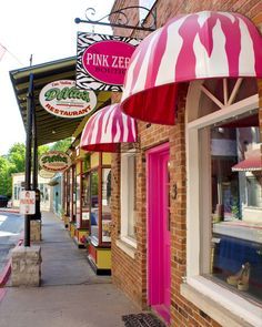 a pink and white striped awning on the side of a building next to a sidewalk