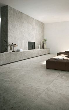 a modern living room with concrete walls and flooring, including a large sectional sofa