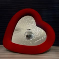 a heart shaped mirror with a disco ball in the center and light reflecting on it