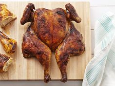 a whole chicken sitting on top of a wooden cutting board next to other pieces of meat