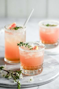 two glasses filled with watermelon lemonade and garnished with fresh herbs