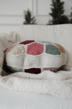 a crocheted turtle pillow sitting on top of a white couch next to a christmas tree