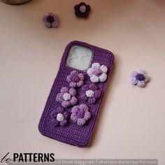 a cell phone case with crocheted flowers on the front and back cover, sitting on a table