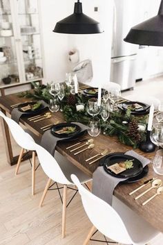 a long table with black plates and white chairs is set up for a festive dinner