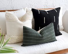 three pillows are sitting on a couch with white and black stripes, one is green