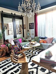 a living room filled with lots of furniture and a chandelier hanging from the ceiling