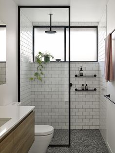 a bathroom with a toilet, sink and shower in it's stall area next to a window