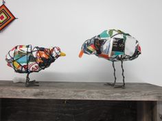 two metal birds made to look like they are standing on top of a wooden table