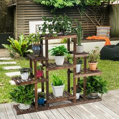 a wooden shelf filled with potted plants in front of a house and sitting area