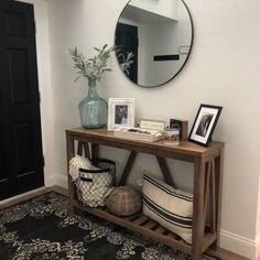 there is a mirror, vase and pictures on the shelf in this entryway area