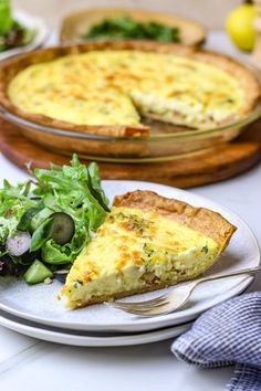 a slice of quiche on a plate next to a salad