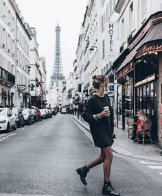 a woman is walking down the street in front of the eiffel tower