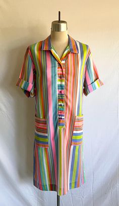 1960's striped house dress with pockets! Dress is a super soft cotton rayon in a fun Mod, multi-colored stripe. Dress is collared with a partial front buttoning placket. Sleeves are half sleeve length with rolled cuff. There are square set on pockets at each hip.  Dress is clean and in great condition! There are 2 small spots on the front of the dress (see photos).  Label: There is a company label, but the lettering has since faded Measurements: would best fit a modern size L Bust= 44"  Hip= 45" Shoulder width= 16 1/2" Sleeve length= 10" Bicep= 15 3/4" Sleeve opening= 15 3/4" Body length from side neck at shoulder down to hem edge= 41" Short Sleeve Cotton Dress With Vertical Stripes, Cotton Short Sleeve Dresses With Vertical Stripes, Cotton Dress With Vertical Stripes And Short Sleeves, Retro Striped Lined Dress, Vintage Short Sleeve Striped Dress, Striped Collared Cotton Dress, Striped Short Sleeve Dresses With Pockets, Striped Cotton Dresses With Pockets, Collared Dress