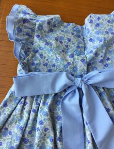 "This beautiful handmade custom dress is made from petite blue floral fabric! The front bodice is lined with blue fabric and buttons in the back. This makes a perfect spring or Easter dress! The length can be customized for your little girl and the dress can be made in a variety of fabrics - just send me a message with your request! I have a size 12 months and and 18 months ready to ship. Features - Sevenberry floral fabric from Robert Kaufman - Double flutter sleeves - Fabric feels crisp and ir Blue Ruffle Dress For Garden Party, Fitted Blue Floral Dress With Ruffles, Fitted Cotton Floral Dress With Ruffles, Fitted Floral Cotton Dress With Ruffles, Buttoned Dresses For Spring Dress-up, Button-detailed Dresses For Spring Dress-up, Spring Dresses With Buttons For Dress-up, Fitted Blue Ditsy Floral Dress, Fitted Blue Floral Dress With Ditsy Print