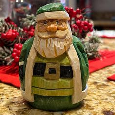 a green gnome figurine sitting on top of a counter next to pine cones