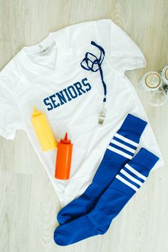 a white shirt with the word seniors on it next to blue socks and other items