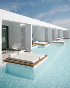 an outdoor swimming pool with lounge chairs next to it and blue sky in the background