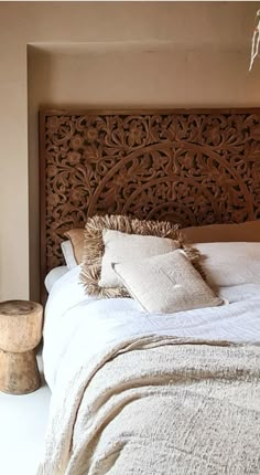 a bed with white linens and pillows on it's headboard in a bedroom