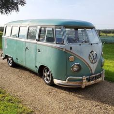 an old vw bus is parked on the side of the road in front of a field