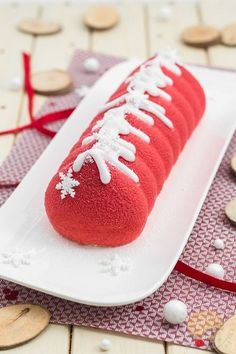 a red hot dog covered in white icing on a plate next to some cookies