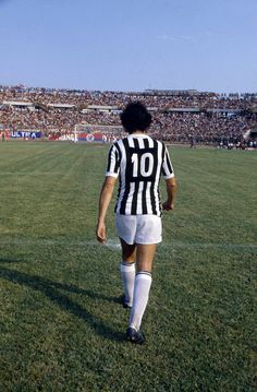 a soccer player is walking on the field in front of an empty stadium full of people