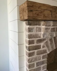 a brick fireplace with a wooden mantel above it