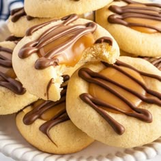 several cookies with peanut butter and chocolate drizzled on top are in a white plate