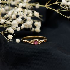 a close up of a ring on a black surface with flowers in the foreground