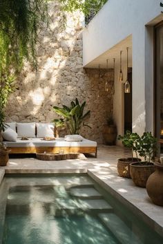 an outdoor living area with couches and potted plants next to a swimming pool