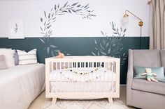 a baby's room with a crib, chair and wall mural in the background