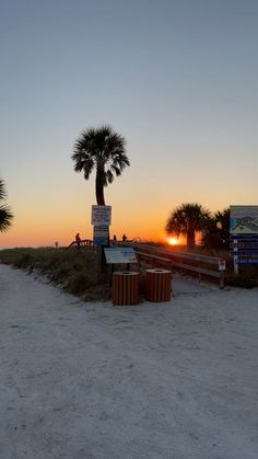 the sun is setting at the beach with palm trees