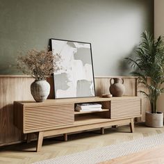 a wooden entertainment center with two vases and a plant on it's stand