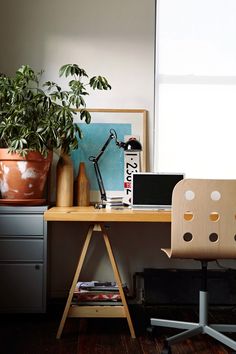 a desk with a chair and potted plant on it