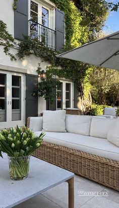 a white couch sitting on top of a patio next to a table with flowers in it