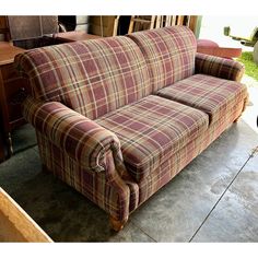 a plaid couch sitting on top of a cement floor