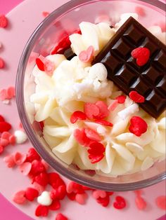 a bowl filled with white and red food next to hearts on a pink tablecloth