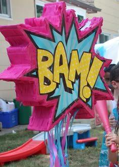 two girls are standing in front of a pink balloon with the word bam on it