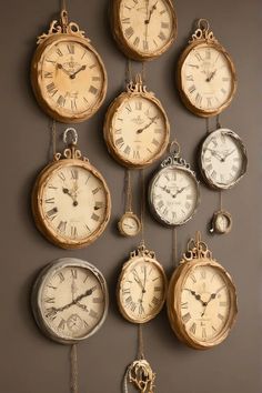 many clocks are hanging on the wall with chains