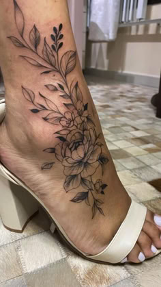 a woman's foot with flowers and leaves on the side of her body,