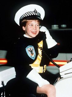 a little boy in a police uniform talking on the phone