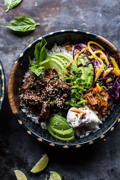 a bowl filled with meat, rice and veggies on top of a table